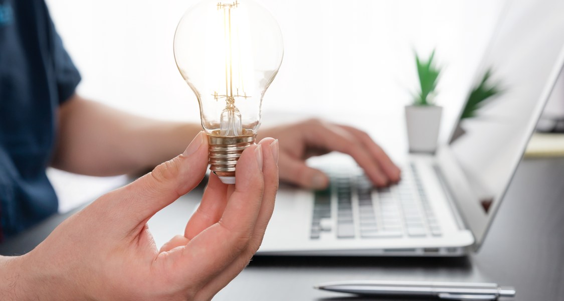 Laptop user holding a light bulb