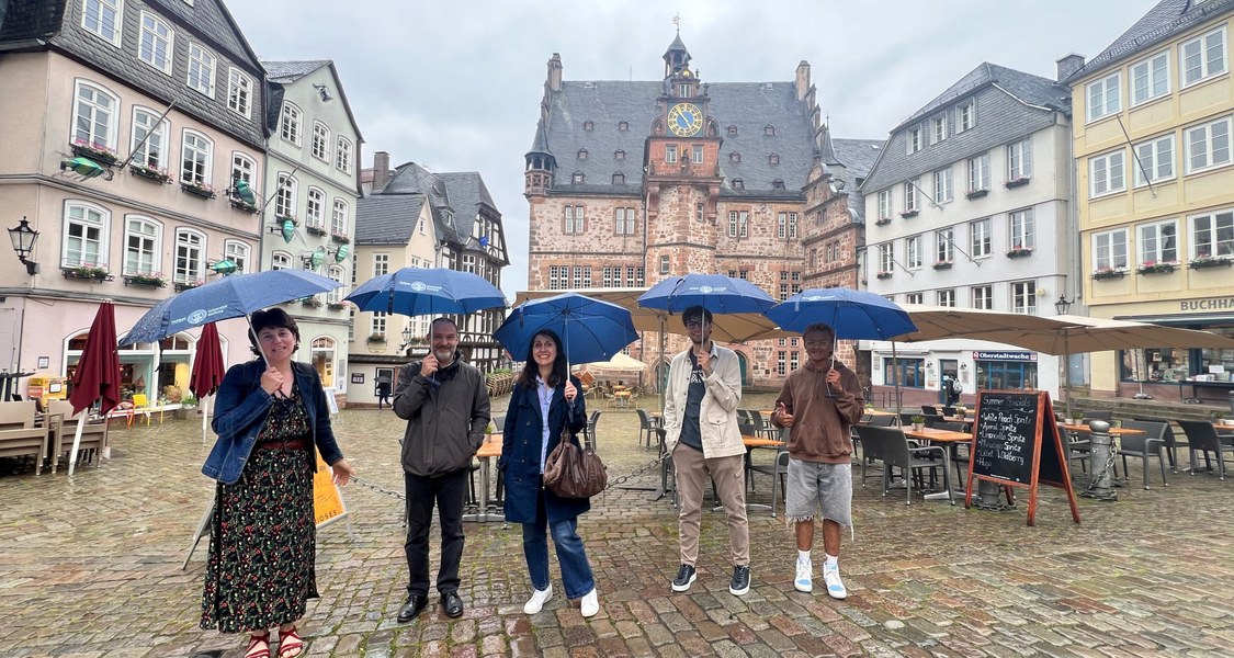 Delegation of administrative Personal form University of Limoges at the Martplatz Marburg in the rain with umbrellas.
