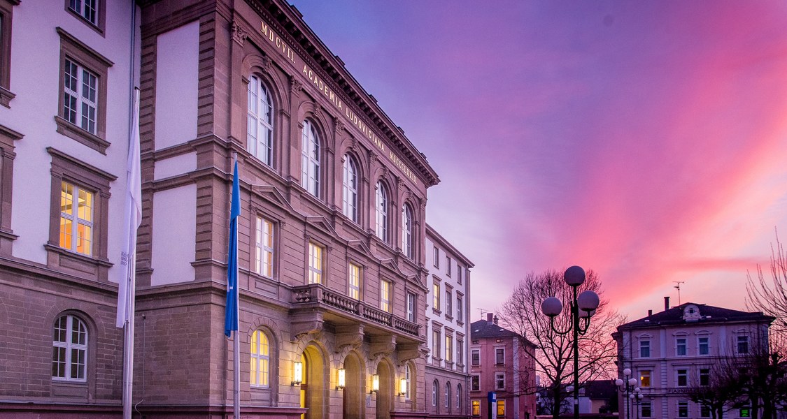 The main building of Justus Liebig University is in the foreground on the left with a beautiful and colourful sky at sunset in the background.